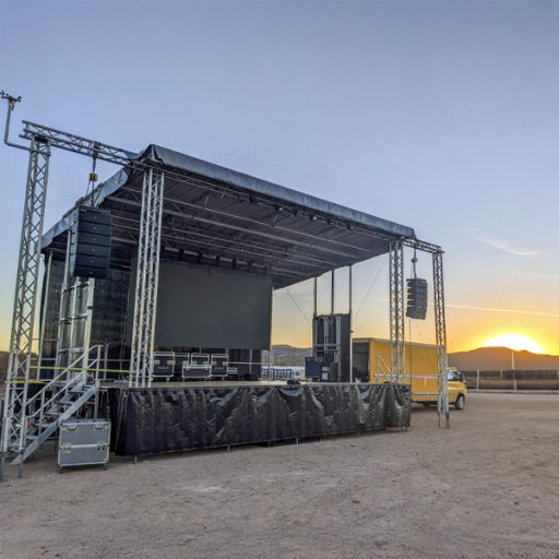Empty stage with digital screen and speakers in a desert at sunset